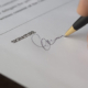 Person signing an official document as part of the Dubai trade licence application process.