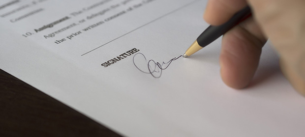 How to Get a Trade Licence in Dubai ‣ Sentinel Dubai Person signing an official document as part of the Dubai trade licence application process.